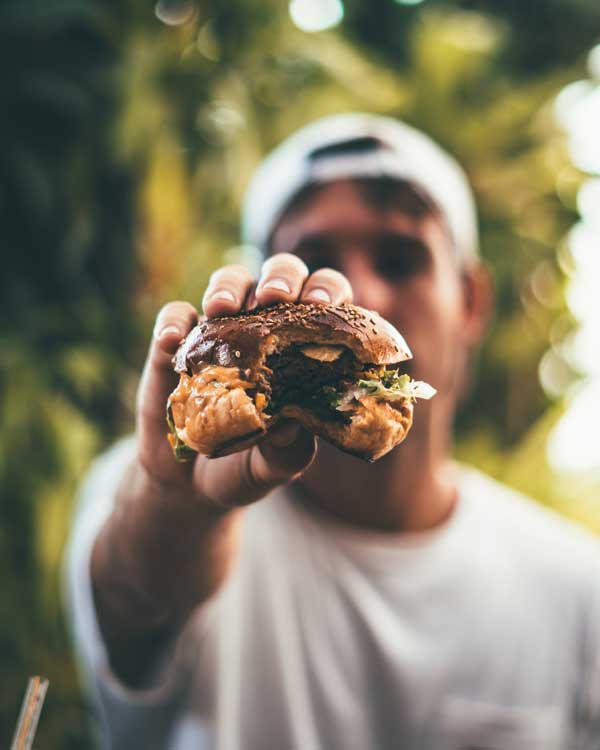 instant gratification. Easy access to fast food. Man holding a burger.